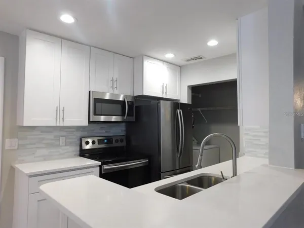 a kitchen with stainless steel appliances a refrigerator a sink a stove a microwave and cabinets