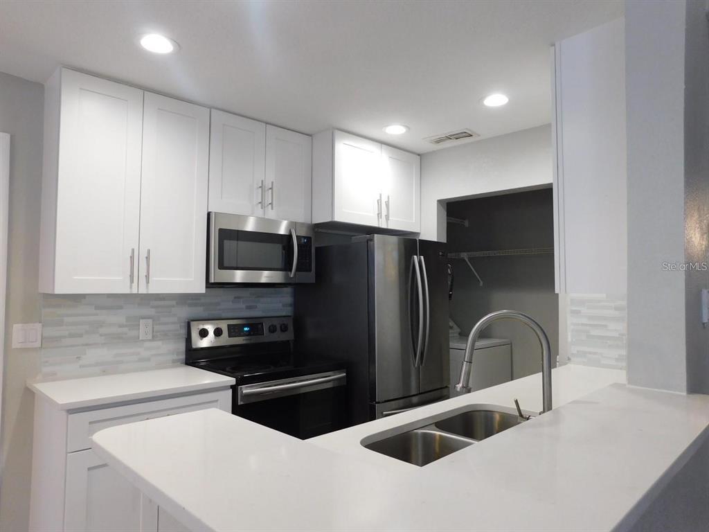 1077 South Hiawassee Road, Unit 823 Orlando, FL 32835 - Photo 8 of 29 a kitchen with stainless steel appliances a refrigerator a sink a stove a microwave and cabinets