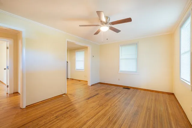 a view of an empty room with wooden floor and a window