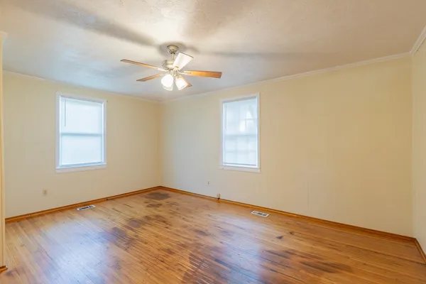 a view of empty room with wooden floor and fan