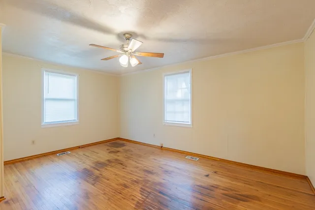 a view of empty room with wooden floor and fan