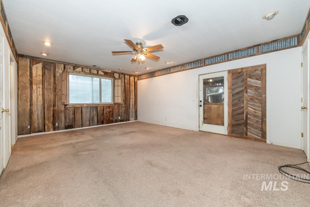 16517 Madison Road Nampa, ID 83687 - Photo 13 of 26 Spare room featuring wooden walls, a ceiling fan, and light colored carpet