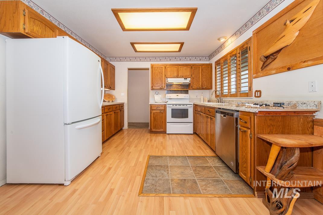 16517 Madison Road Nampa, ID 83687 - Photo 7 of 26 Kitchen with light countertops, white appliances, brown cabinets, light wood-style flooring, and under cabinet range hood