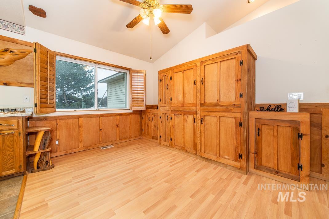 16517 Madison Road Nampa, ID 83687 - Photo 9 of 26 Unfurnished dining area featuring a wainscoted wall, lofted ceiling, light wood-type flooring, and a ceiling fan