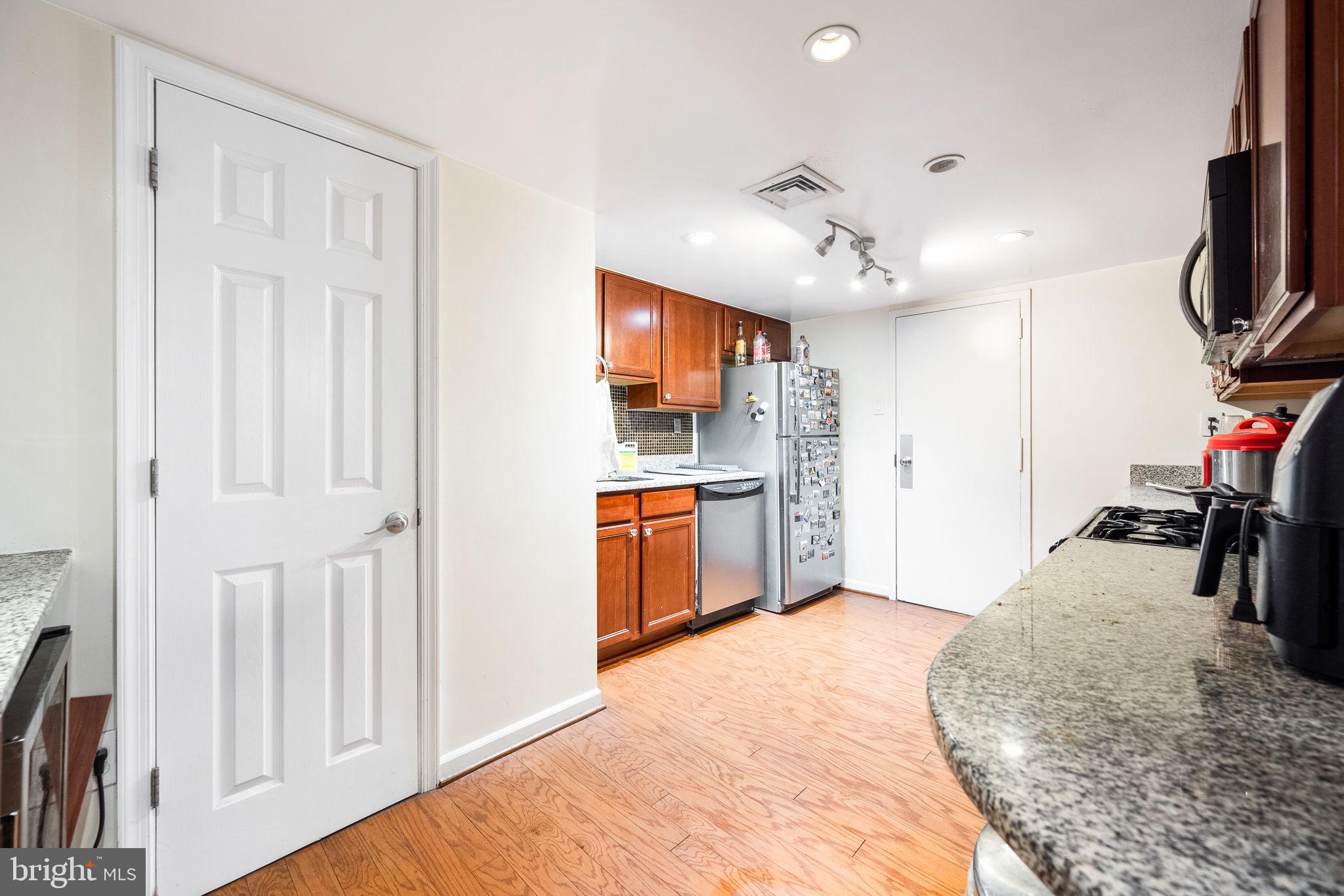 1515 South Arlington Ridge Road, Unit 303 Arlington, VA 22202 - Photo 17 of 34 a kitchen with kitchen island a stove a sink and a refrigerator with wooden floor