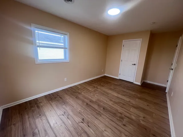 a view of empty room with wooden floor