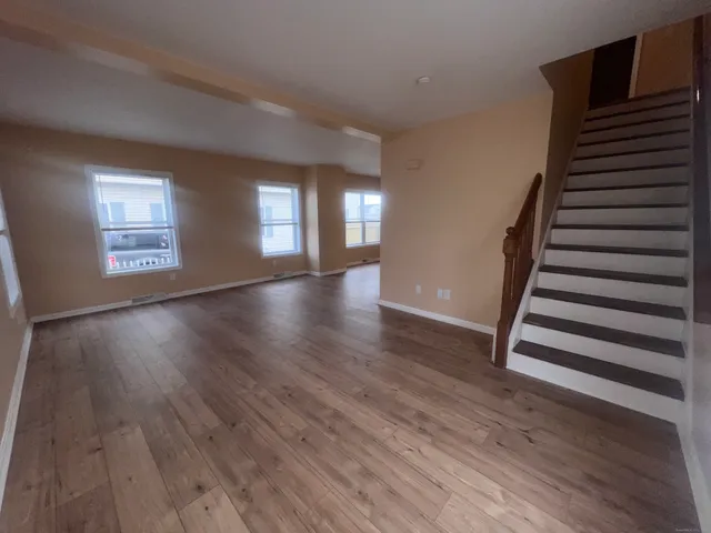 a view of an empty room with wooden floor and windows