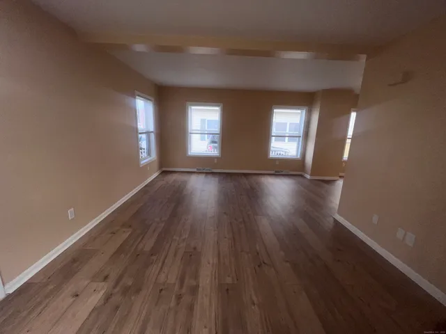 a view of an empty room with wooden floor and window