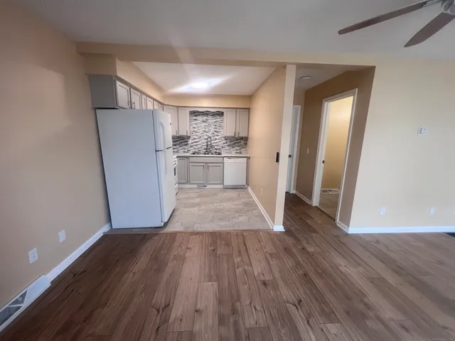 a view of a room with wooden floor and a refrigerator