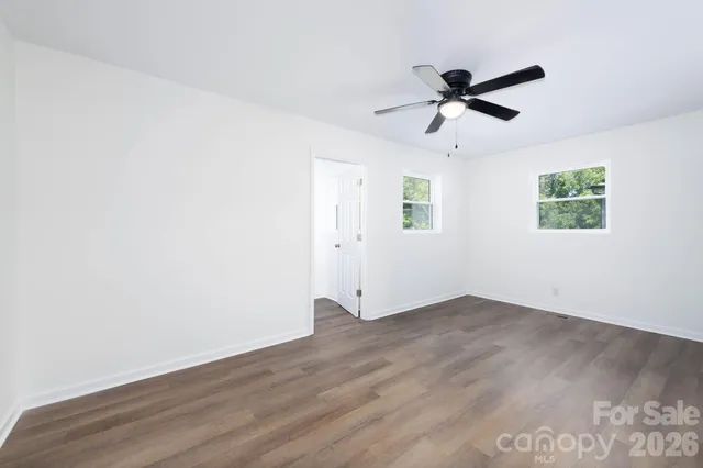 an empty room with wooden floor closet and windows