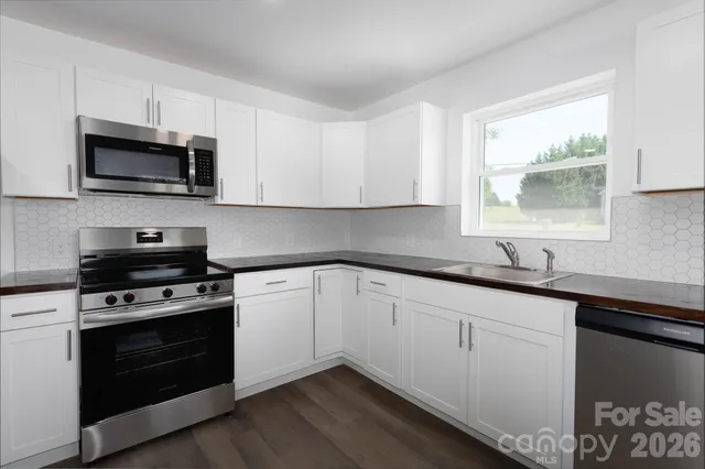 a kitchen with stainless steel appliances granite countertop a sink dishwasher a stove and a microwave oven with cabinets