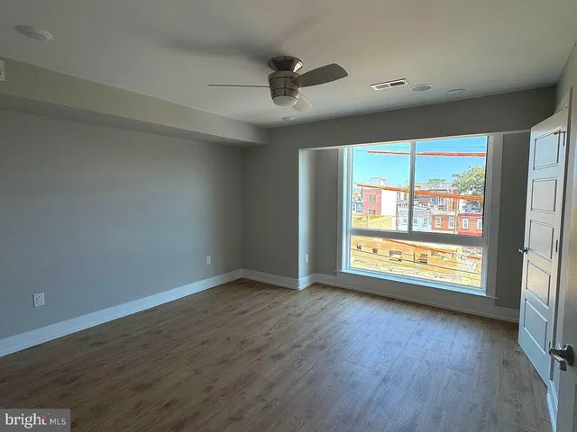 an empty room with wooden floor and windows