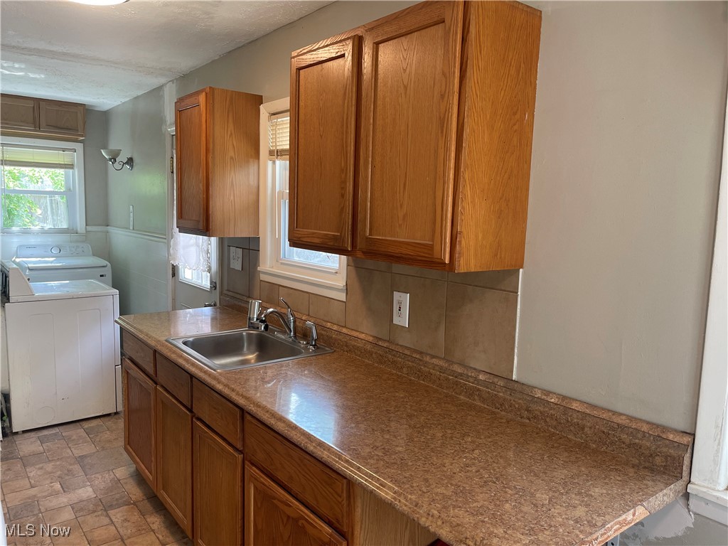 353 Gibbs Road Akron, OH 44312 - Photo 9 of 15 Kitchen featuring separate washer and dryer, brown cabinetry, and stone finish floors