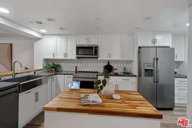a kitchen with kitchen island granite countertop a sink stainless steel appliances and white cabinets