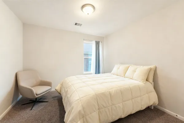 a large bed sitting in a bedroom next to a window and a chair