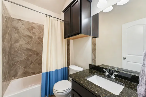 a bathroom with a granite countertop sink toilet and shower