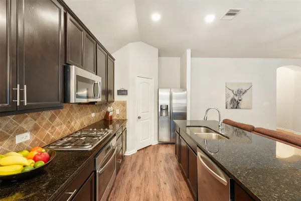 a kitchen with stainless steel appliances granite countertop a sink stove and refrigerator