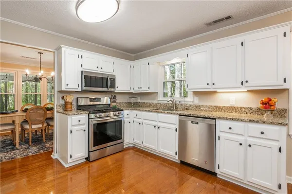 a kitchen with granite countertop white cabinets and white appliances