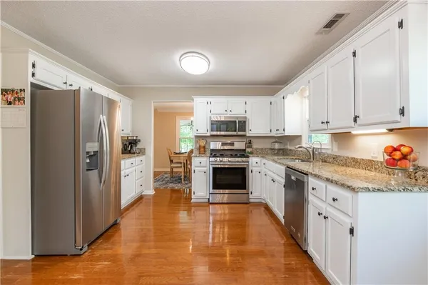 a kitchen with granite countertop a refrigerator stove top oven and cabinets