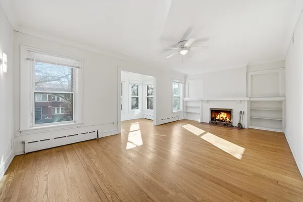 an empty room with wooden floor fireplace and windows