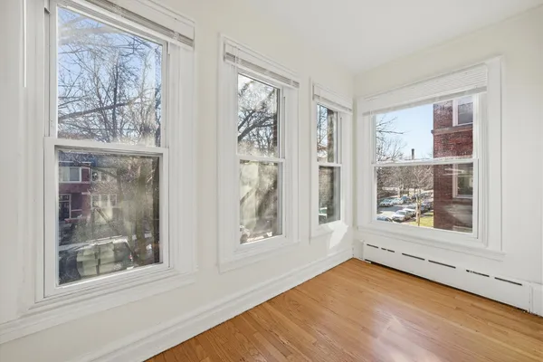 a view of an empty room with a window and wooden floor
