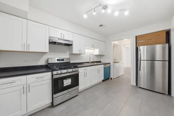 a kitchen with stainless steel appliances granite countertop a refrigerator a sink a stove and white cabinets