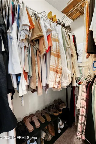 a view of walk in closet with clothes and shoes