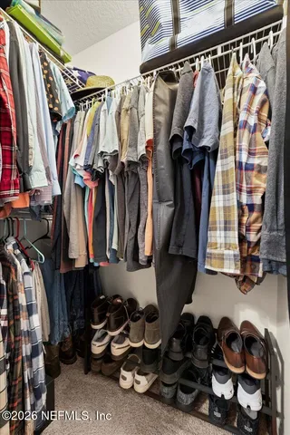 a view of walk in closet with clothes and shoes