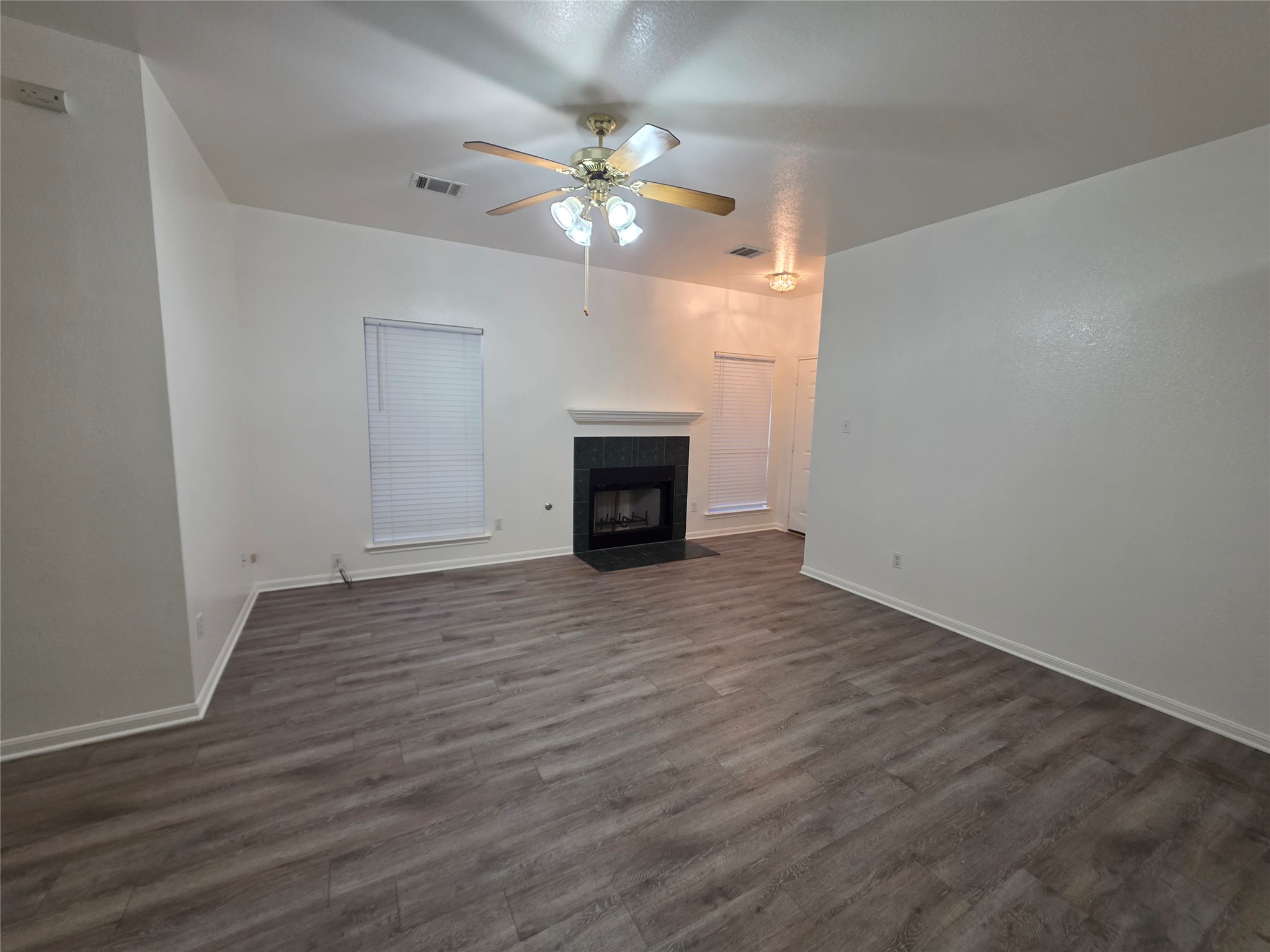 4417 Lendall Lane Austin, TX 78744 - Photo 2 of 23 a view of an empty room with wooden floor and a fireplace