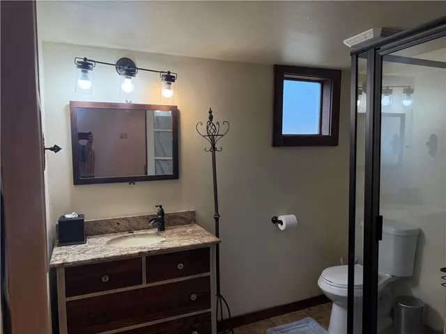 a bathroom with a granite countertop toilet sink and mirror