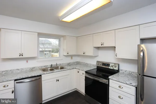 a kitchen with granite countertop white cabinets and white appliances