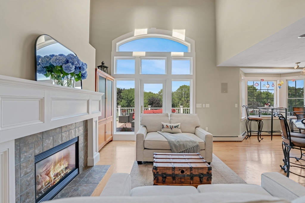 57 Perry Hill Road Acushnet, MA 02743 - Photo 12 of 40 a living room with furniture a fireplace and a large window with balcony view