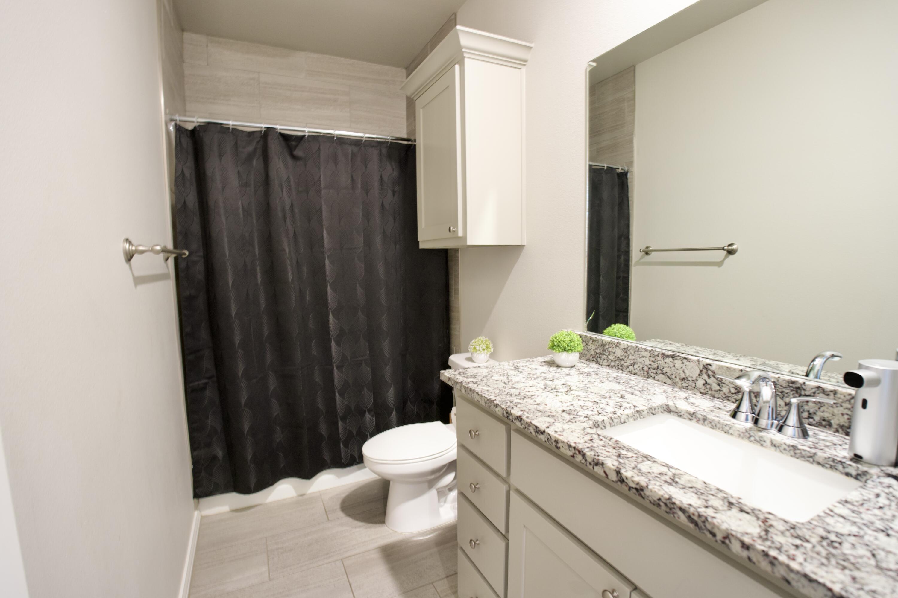 5801 Winfield Avenue Lubbock, TX 79407 - Photo 13 of 20 a bathroom with a granite countertop sink and a mirror with toilet