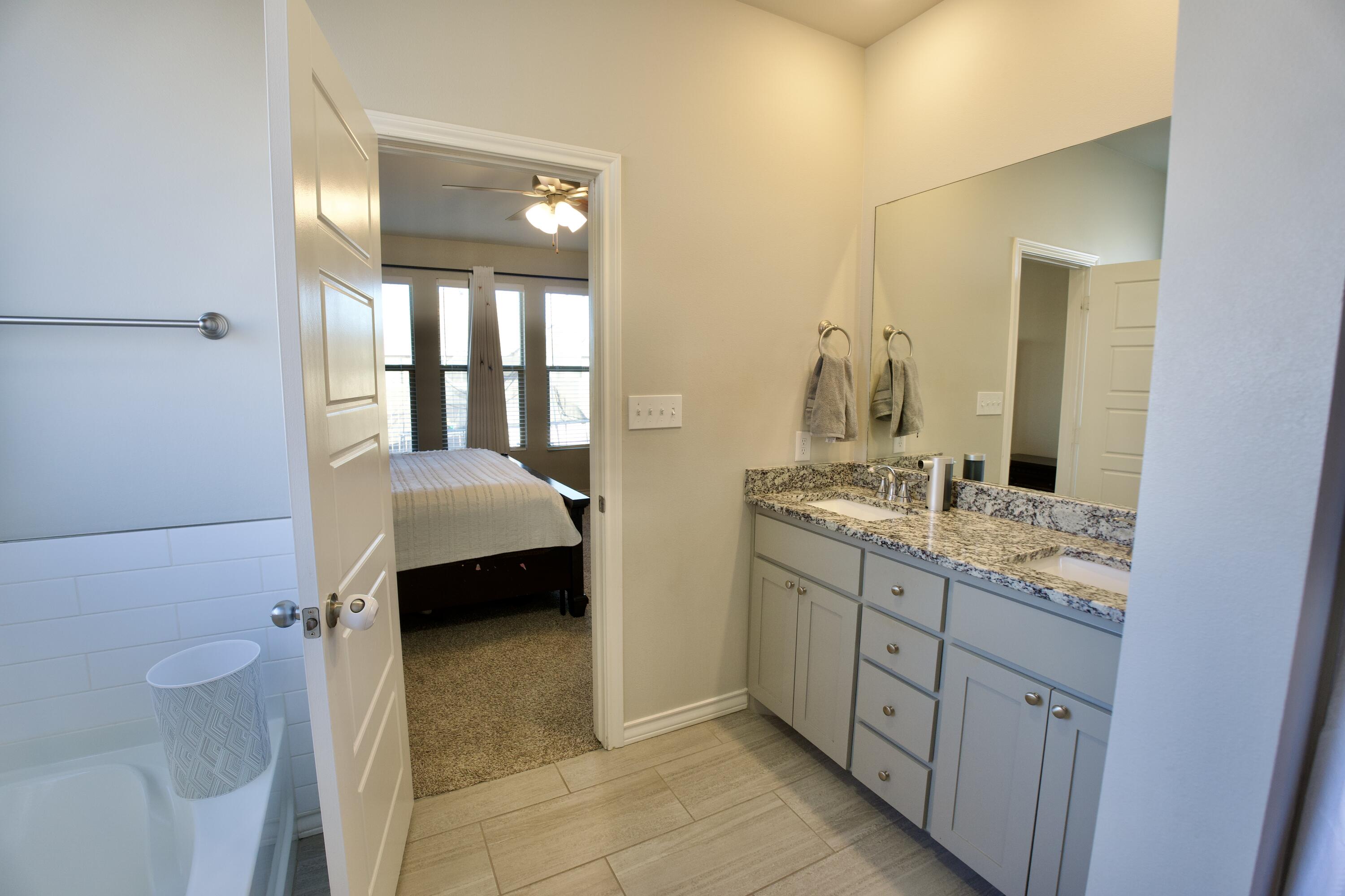 5801 Winfield Avenue Lubbock, TX 79407 - Photo 10 of 20 a en suite bathroom with a granite countertop sink and a mirror