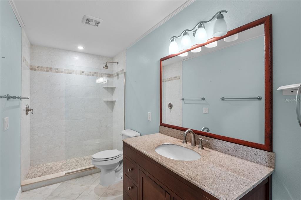 3840 Mariners Way, Unit 525 Cortez, FL 34215 - Photo 22 of 48 a bathroom with a granite countertop sink a toilet a mirror and shower