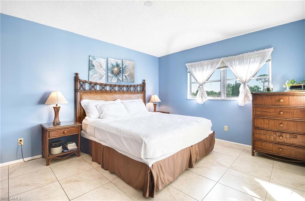 5483 Rattlesnake Hammock Road, Unit 207 Naples, FL 34113 - Photo 8 of 15 Bedroom featuring a textured ceiling and light tile patterned floors