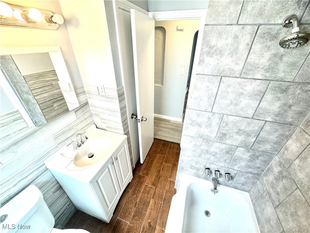 1215 Avondale Road Cleveland, OH 44121 - Photo 21 of 27 Bathroom with a bathing tub, hardwood / wood-style floors, tile walls, toilet, and vanity