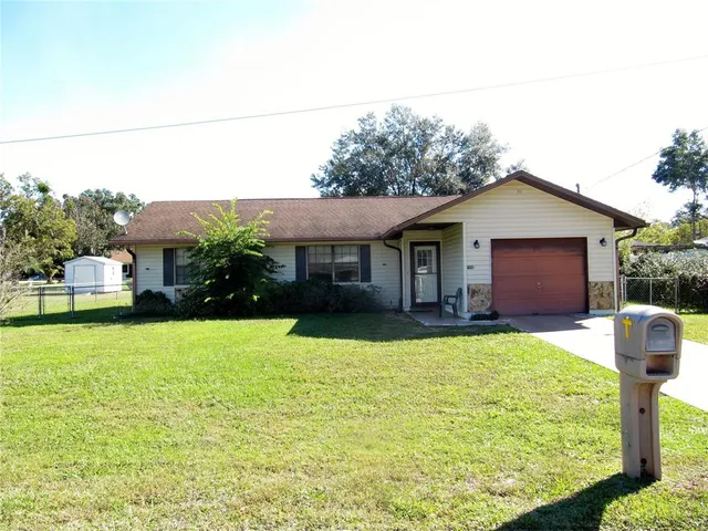 a front view of house with yard and trees in the background