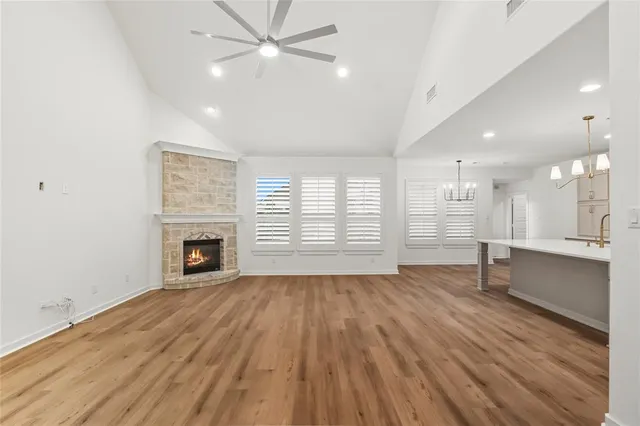 an empty room with wooden floor fireplace and windows