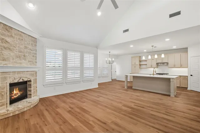 a large kitchen with stainless steel appliances wooden floor and a fireplace