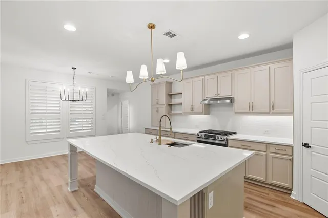 a kitchen with kitchen island a sink a stove and cabinets
