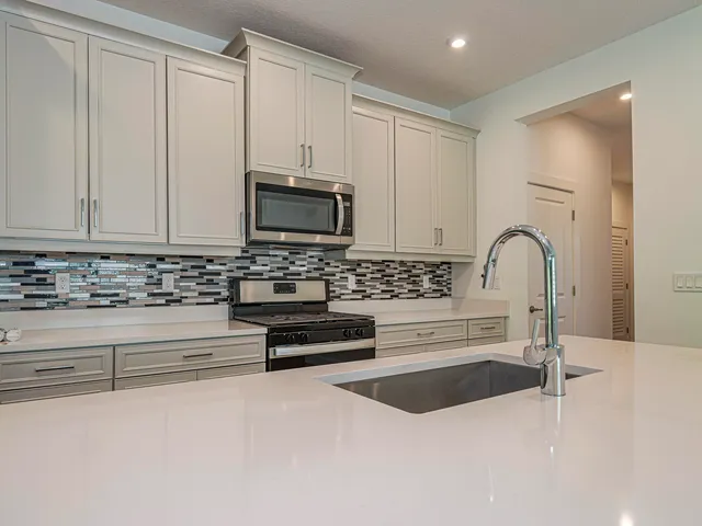 a kitchen with granite countertop white cabinets and stainless steel appliances