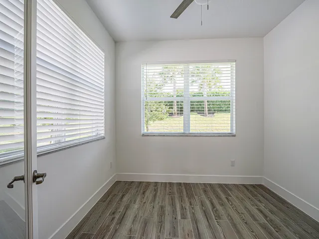 a view of an empty room with wooden floor and a window