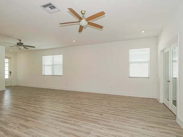an empty room with wooden floor fan and windows
