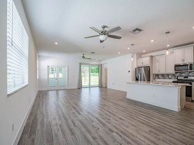 a view of kitchen with cabinets wooden floor and a ceiling fan