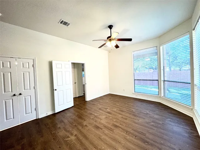 a view of empty room with wooden floor and fan