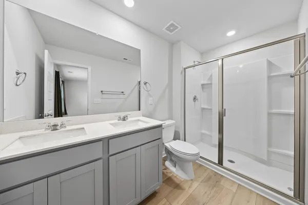 a bathroom with a double vanity sink toilet and shower