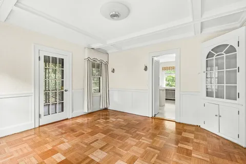 a view of an empty room with glass door and wooden floor