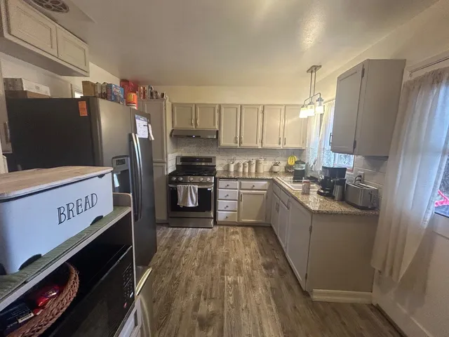 a kitchen with stainless steel appliances a refrigerator a stove a sink and white cabinets