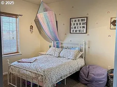 a bedroom with a bed a painting on the wall and a window